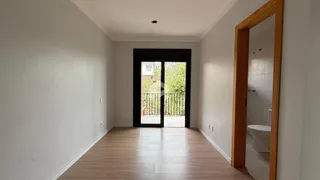 Corredor interno de uma residência com piso de madeira e porta de vidro.