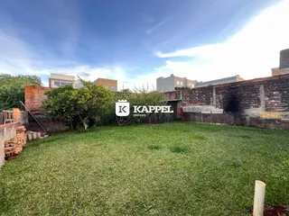 Área externa com gramado verde e muro de tijolos ao fundo.
