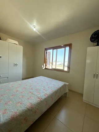 Quarto com cama e armários brancos em um imóvel no Brasil.