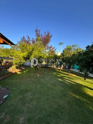 Vista de um gramado com árvores sob um céu azul claro.