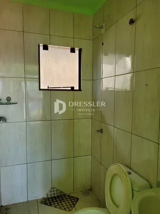 Parede interna de um banheiro com revestimento de azulejos claros.