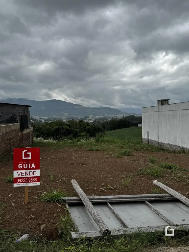 Vista da propriedade com muro e paisagem ao fundo.