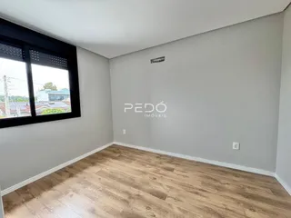 Ambiente interno com piso de madeira clara e grande janela.