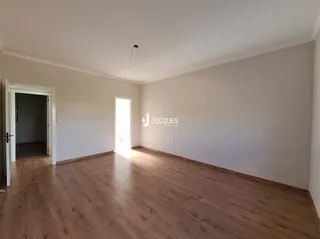 Interior de uma sala com piso de madeira clara.