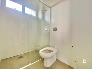 Foto de um banheiro interno com azulejos claros e um vaso sanitário branco.