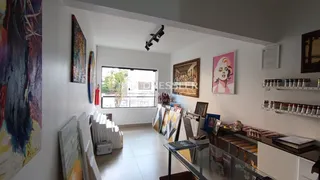 Interior de uma sala de estar clara com grande janela e decoração de parede.