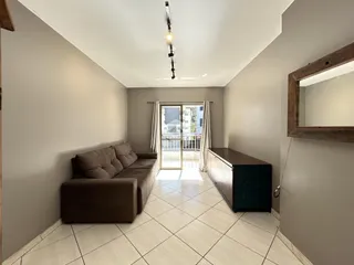 Sala de estar com sofá e móveis de madeira em um apartamento.