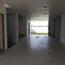Hall de entrada com piso de concreto e paredes brancas.