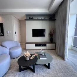 Sala de estar com sofá e televisão montada na parede.