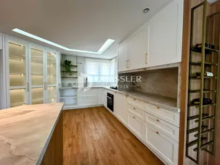 Cozinha moderna com armários brancos e piso de madeira clara.