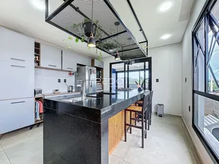 Cozinha moderna com ilha e grandes janelas em um imóvel no Brasil.
