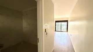 Hall de entrada com paredes brancas e piso claro em uma residência.
