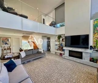Sala de estar moderna com escadaria e televisão na área interna.
