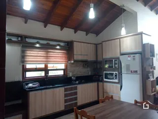 Interior de uma cozinha com armários de madeira e bancadas escuras.