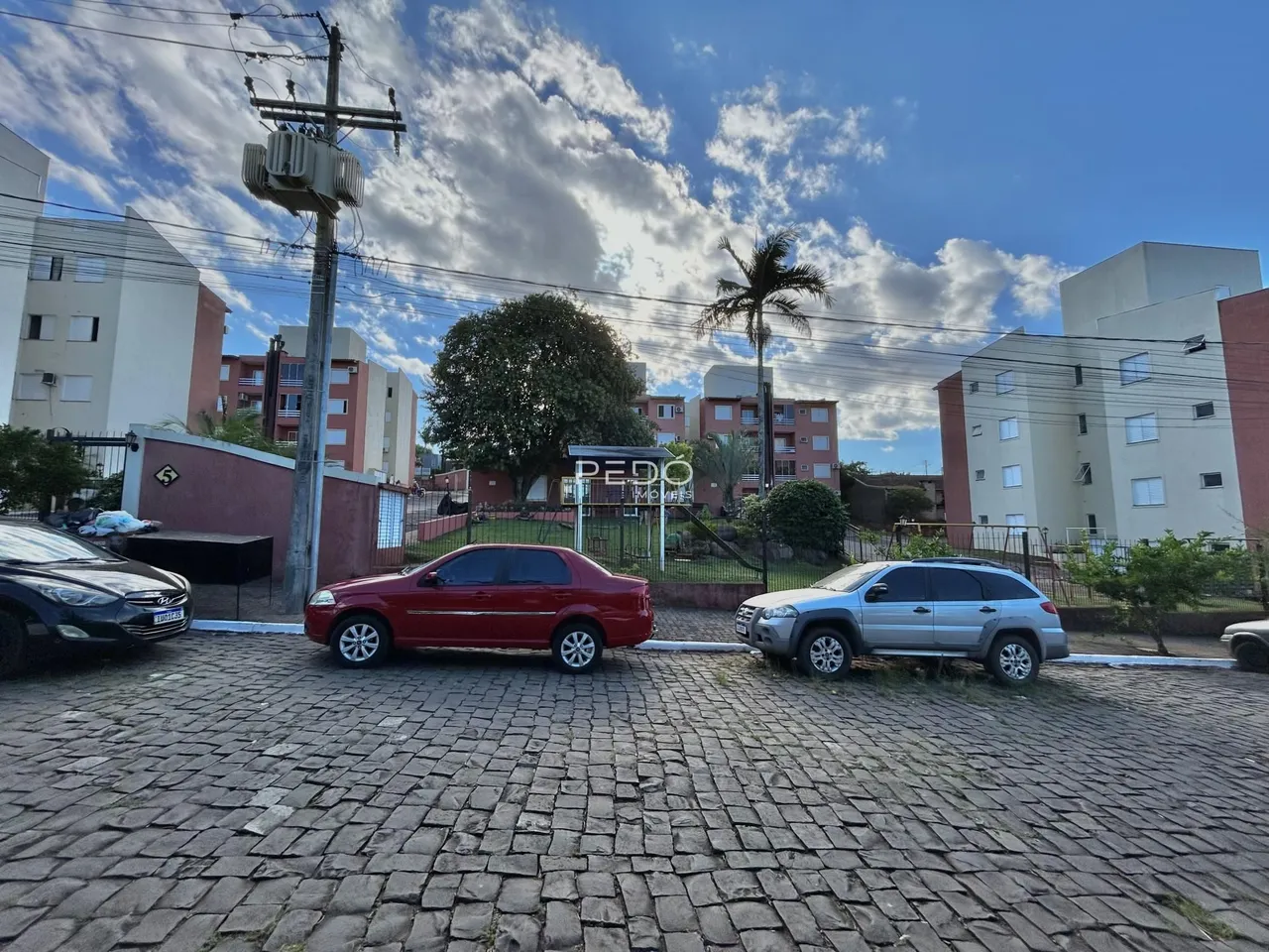 Vista da fachada de uma residência em Lajeado, Brasil, com carros estacionados na frente.