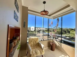Vista de uma sala com grande janela que oferece uma paisagem verde.