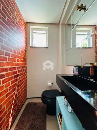 Foto de um ambiente interno com parede de tijolos aparentes e um vaso sanitário.