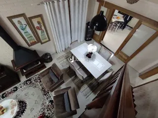 Imagem de uma sala de estar com piso de madeira e tapete no interior de uma residência.