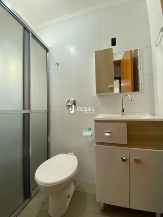 Foto interna de um banheiro com vaso sanitário e azulejos brancos.
