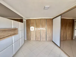 Quarto com cabeceira branca e armários de madeira na parede.
