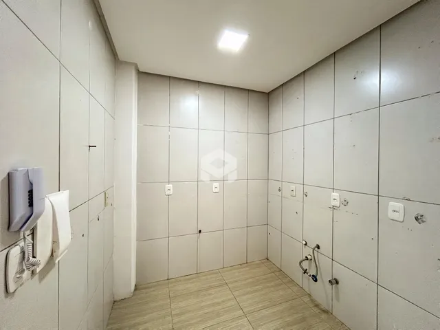 Vista interna de um corredor com paredes e piso revestidos de cerâmica.