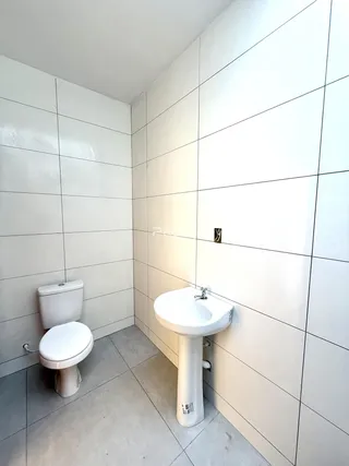 Foto de um banheiro com revestimento cerâmico nas paredes brancas.