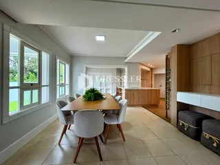 Uma sala de jantar com mesa de madeira e grandes janelas.