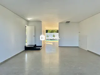 Um corredor amplo e moderno com piso de concreto polido e paredes brancas.