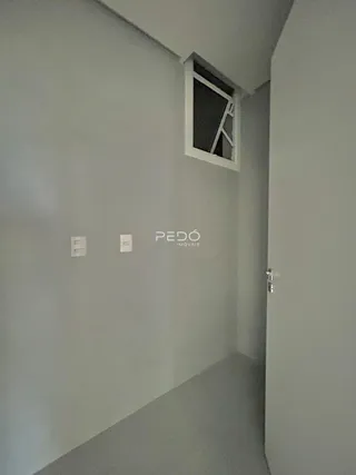 Vista de um corredor interno com parede cinza e uma janela no canto de uma residência.