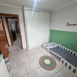 Um quarto com armários brancos e piso de cerâmica clara.