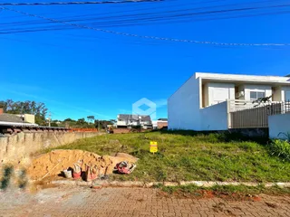 Vista externa de uma residência branca com terreno gramado e terra no primeiro plano.