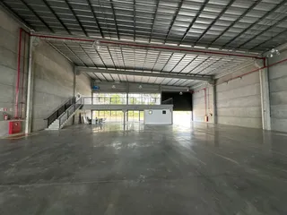 Espaço interno amplo com teto metálico e piso de concreto.
