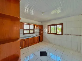 Interior de uma cozinha com armários de madeira e piso de cerâmica branca.