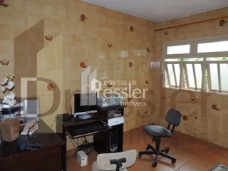 Interior de uma sala com paredes de azulejo e móveis escuros.
