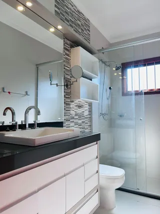 Foto de um banheiro moderno com box de vidro e bancada branca.