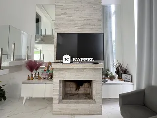 Sala de estar com lareira de pedra e televisão moderna.