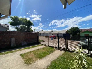 Vista externa de uma propriedade com muro de tijolos e cerca de madeira.