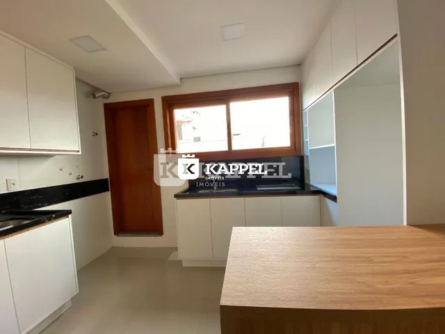 Uma cozinha moderna com armários brancos e bancadas escuras.