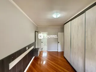 Hall de corredor com piso de madeira e armários embutidos brancos.