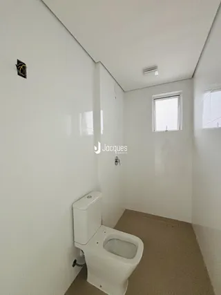 Foto de um banheiro interno com paredes brancas e piso bege.