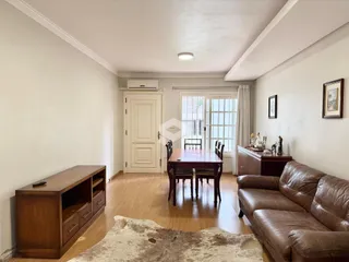 Sala de estar com piso de madeira e sofá marrom.