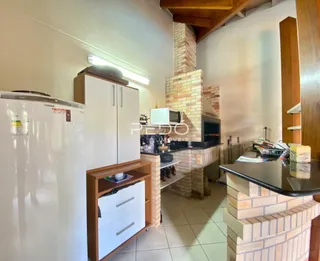 Imagem de uma cozinha com armários brancos e parede de tijolos aparentes.