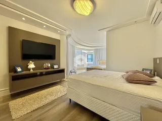 Quarto com cama grande e televisão montada na parede em um imóvel em Lajeado.