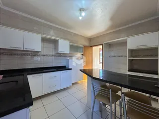 Imagem de uma cozinha com armários brancos e bancadas escuras.
