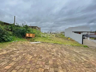 Vista externa de um terreno pavimentado com vegetação ao fundo.