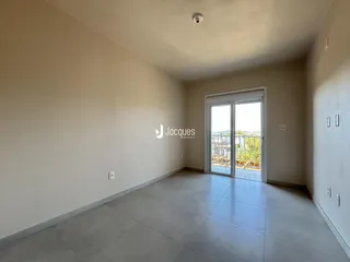 Ambiente interno de uma sala com piso de concreto e porta de vidro.