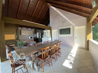 Vista de uma sala de jantar com mesa de madeira e piso cerâmico em uma casa no Brasil.