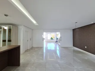 Interior de um espaço aberto com piso de cerâmica clara e teto inclinado.