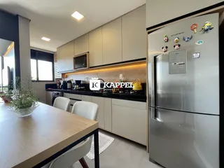 Cozinha moderna com armários claros e bancadas escuras em um ambiente bem iluminado.