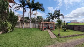 Vista externa de um jardim com gramado e uma estrutura de madeira em Lajeado.